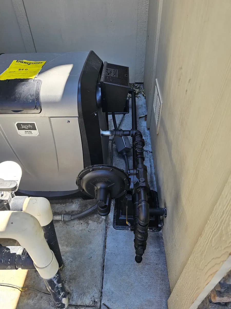 Black iron gas piping routed beside pool heater equipment